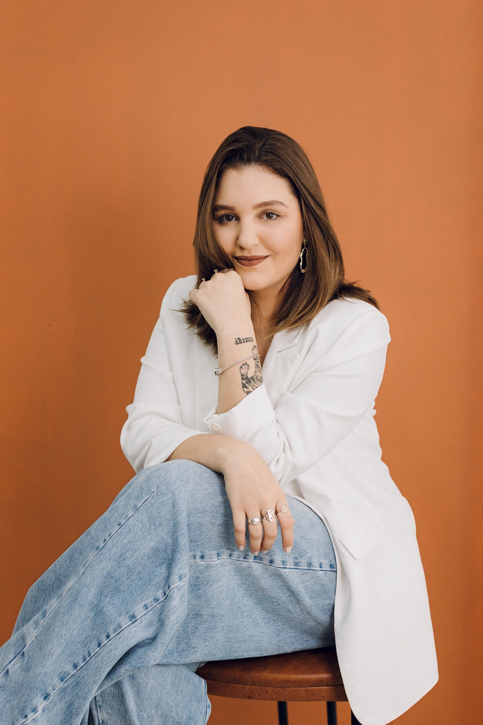 Katelyn Santos, fundadora da Perspectiva, sentada diante de um fundo laranja